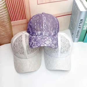 Detail of lace baseball caps in purple, beige, and white with floral patterns