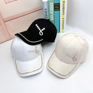 Dettaglio di cappelli da baseball alla moda con accenti di perle e catena di strass sulla visiera