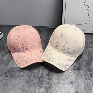 Pink and beige baseball caps with silver star rhinestones on marble background