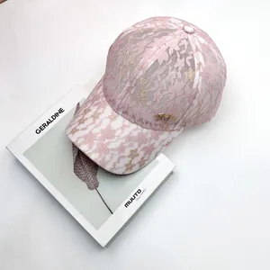 Detail of pink lace baseball cap featuring floral texture and golden metal M letter logo