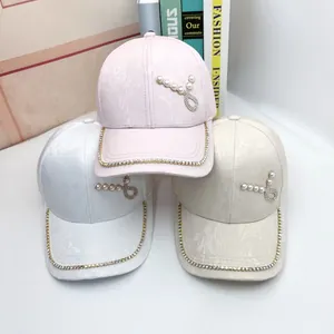 Dettaglio di cappelli da baseball in seta con perle e tesa con strass colorati