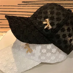 Detail of floral lace baseball caps with rhinestone bow decoration in black and white