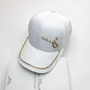 Dettaglio cappello jacquard bianco con cuore di perle e catena di strass lucidi