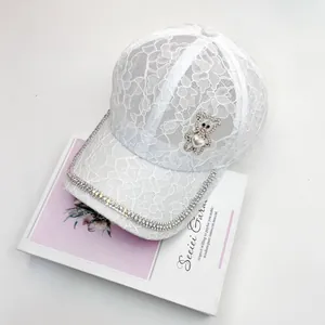 Détail d'une casquette en dentelle blanche avec ours en strass et cœur perlé élégant
