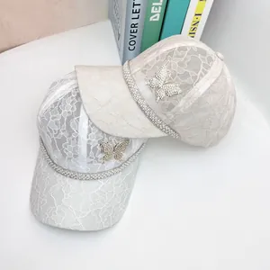 Detail of floral lace baseball caps with rhinestone butterfly and pearl trim