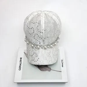 Detailed view of white lace baseball cap featuring elegant sequins and pearl rhinestone chain