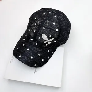 Detailed view of black lace baseball cap with sparkling rhinestones and butterfly badge