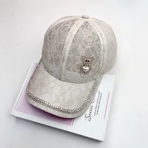 Vue détaillée de la casquette en dentelle florale beige avec ours en strass et perles