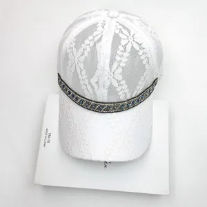 Detailed close-up of white floral lace fabric and crystal bead trim on the baseball cap