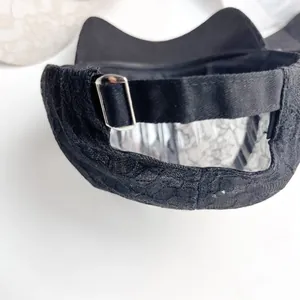 Close-up of black lace fabric texture and adjustable silver metal buckle on the back of the cap