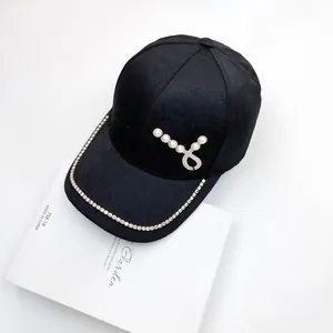 Dettaglio cappello baseball jacquard nero con bordo di strass e decorazione a cuore di perle