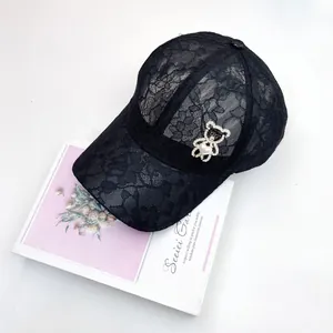 Détail de la casquette en dentelle noire avec une broche d'ours en perles et strass