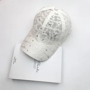 Detail of white floral lace baseball cap with sparkling rhinestones and crystal butterfly