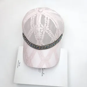 Detailed view of pink floral lace baseball cap with blue and silver rhinestone trim