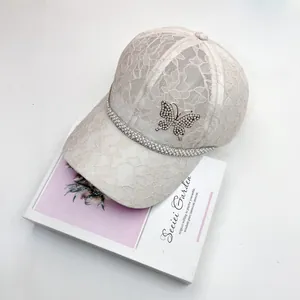 Close-up of lace baseball cap featuring a rhinestone butterfly and pearl trim detail