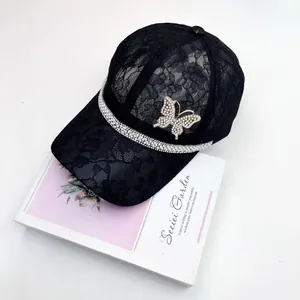 Close-up of black lace baseball cap with sparkling rhinestone butterfly and crystal trim
