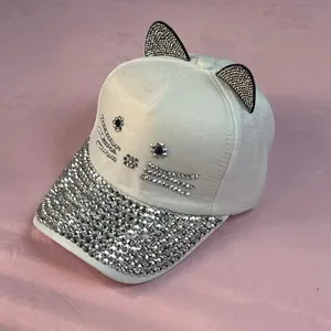 Dettaglio cappellino bianco con orecchie di gatto e strass argentati luccicanti