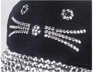 Dettaglio del ricamo a gatto in strass scintillanti su un cappellino da baseball nero