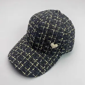 Detailed view of black tweed baseball cap with gold threads and pearl heart decoration