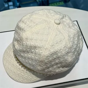 Détail de la casquette gavroche en tweed crème avec chaîne de perles décorative