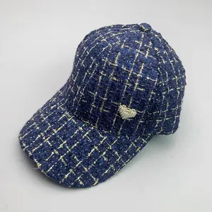 Detail of tweed baseball cap with gold grid lines and pearl heart ornament