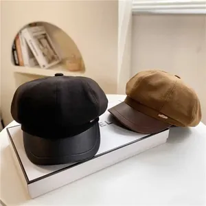 Detail of wool fabric and PU leather brim newsboy caps with gold hardware accents