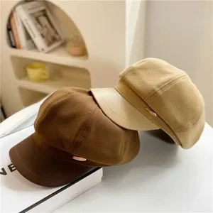 Detail view of wool newsboy hats with leather brims and golden metal accents