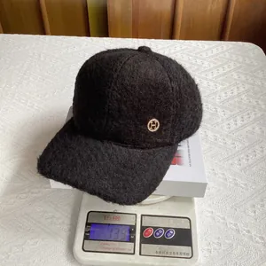 Detail showing weight of black plush wool baseball cap with golden H metal emblem