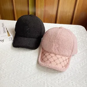 Detalle de gorras de béisbol de lana de cordero en negro y rosa con patrón de letra R