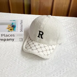 Detalle de gorra de béisbol de lana de cordero blanca con letra R bordada y visera