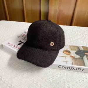 Close-up of black bouclé wool baseball cap featuring a decorative gold metal H logo