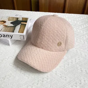 Detail of pink faux shearling baseball cap featuring a golden metal H logo on the side