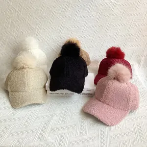 Macro view of teddy fleece baseball caps with faux fox fur pom poms in multiple colors