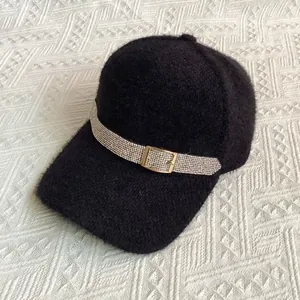 Close-up of black plush baseball cap with rhinestone chain and golden buckle detail