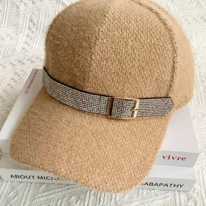 Detail showing sparkling rhinestone belt strap and golden buckle on camel plush baseball cap