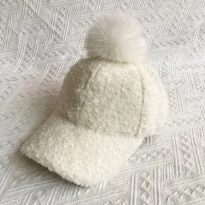 Detail of soft white faux fur pom-pom on a fuzzy plush winter baseball cap texture