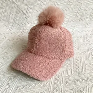 Close-up of pink faux fur pompom and soft lamb wool texture on a winter baseball cap