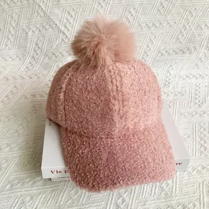 Close-up of pink sherpa baseball cap featuring a large faux fur pom-pom on top