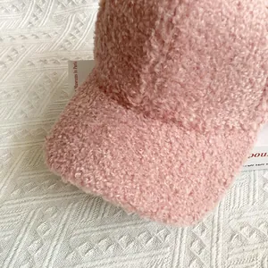 Close-up of pink faux lamb wool fabric texture on a soft baseball cap for women