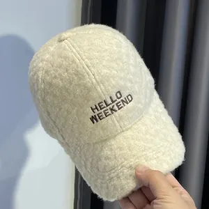 Detail van HELLO WEEKEND borduursel op de crème faux kasjmier baseballpet voor de winter