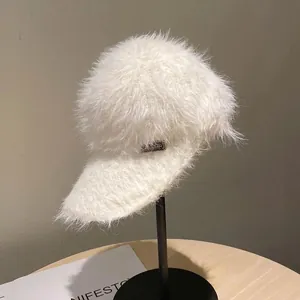 Detail of white mohair open top cap featuring a soft faux fur texture and metal nameplate