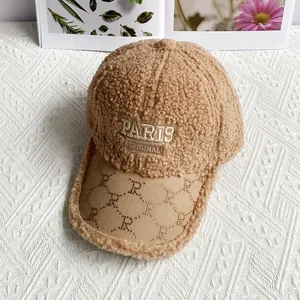 Detailed macro view of embroidered Paris logo on warm camel faux shearling baseball cap