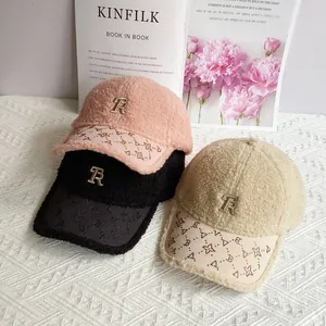 Dettaglio cappellino in peluche con tesa decorata di strass e logo metallico con lettera TR