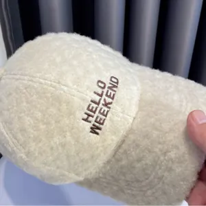 Detail van beige imitatie kasjmier baseballpet met Hello Weekend borduursel