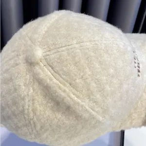 Detailopname van beige fleece baseballcap met bruin geborduurde letters aan de zijkant