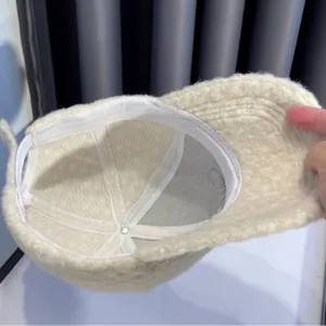 Binnenkant van een beige baseballpet van imitatiekasjmier met witte zweetbandstiksels