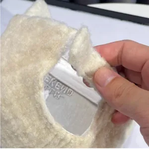 Detailopname van crèmekleurige imitatie kasjmier pet met klittenband en geborduurd label