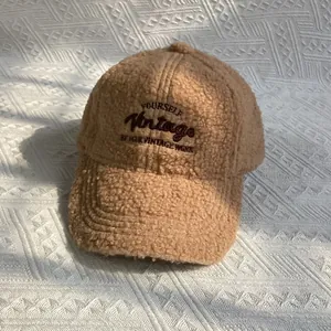 Gros plan sur la texture épaisse en polaire et la broderie vintage de la casquette kaki