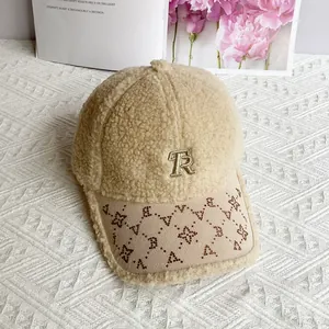 Dettaglio del berretto in lana d'agnello beige con ricamo TR e stelle di strass lucidi