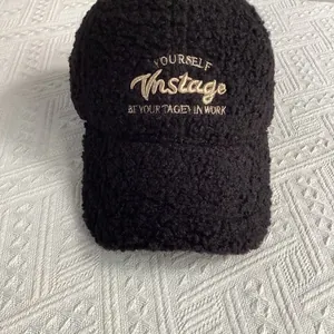 Détail d'une casquette en laine d'agneau noire avec broderie dorée sur le devant